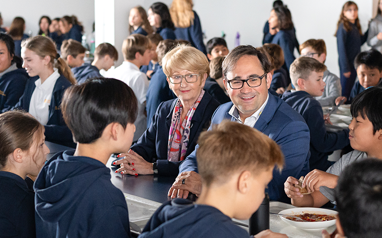 Die Gründerfamilie inmitten von Schülerinnen und Schülern in der Cafeteria